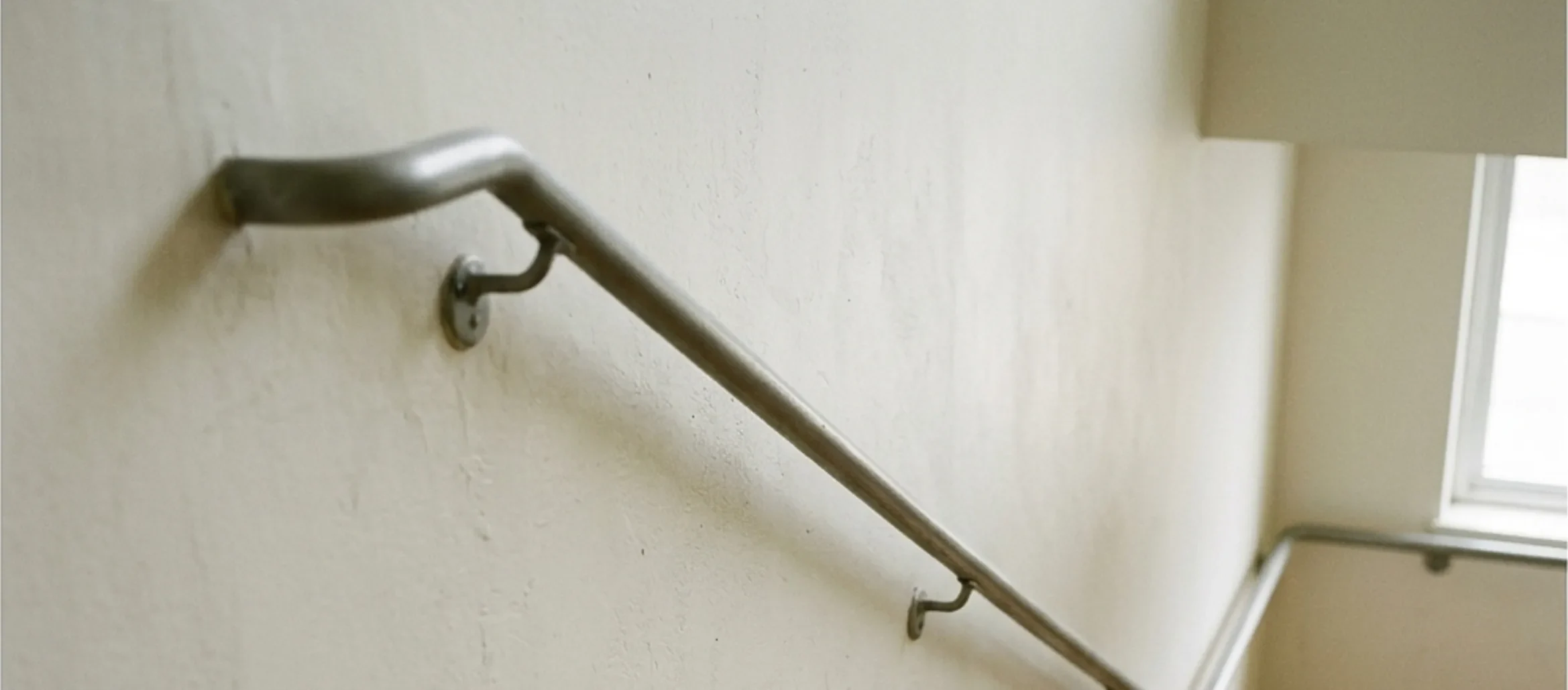 A metal handrail along a flight of stairs in a municipal building stairwell.